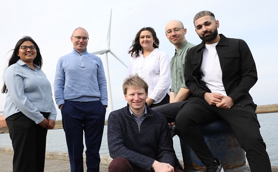 The Kinewell Team standing in front of a wind turbine